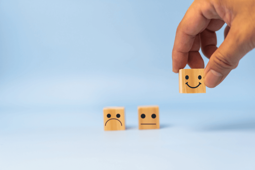 4 Powerful Ways Gamification is Revolutionizing Modern Marketing 9 Hand selecting a smiling face block among neutral and sad face options, symbolizing customer satisfaction and preference.